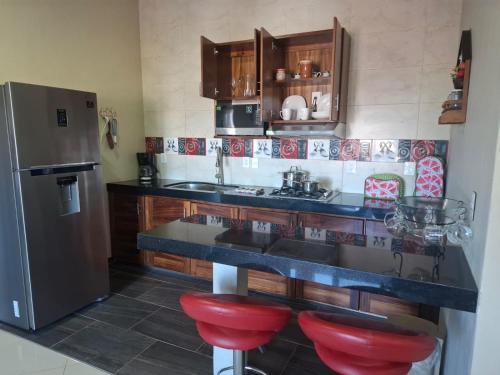 eine Küche mit einer Theke, einem Kühlschrank und roten Stühlen in der Unterkunft Departamentos La Roca D7 in La Peñita de Jaltemba