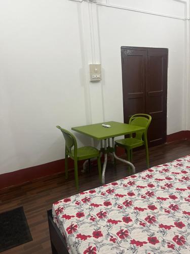 una habitación con una mesa y sillas y una cama en Sri Sam Homestay, en Sibsāgar