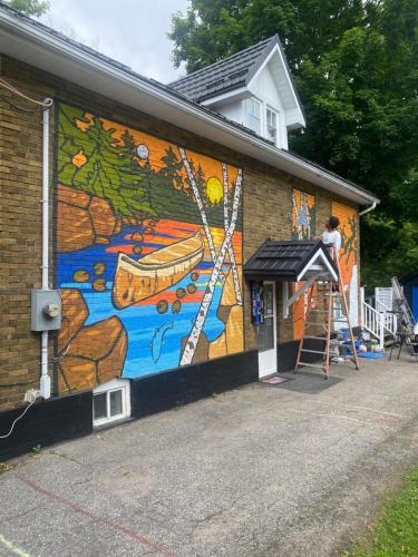 a person painting a mural on the side of a building at Blue Spruce Bed and Breakfast Muskoka in Gravenhurst