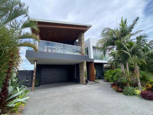 a modern house with a balcony and palm trees at East Woonona Sea Esta Studio in Woonona