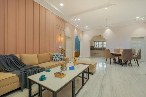 a living room with a couch and a table at SaffronStays Mont Tierra - 4BR modern villa with lawn, bonfire, indoor games & themed rooms, Dehradun in Dehradun