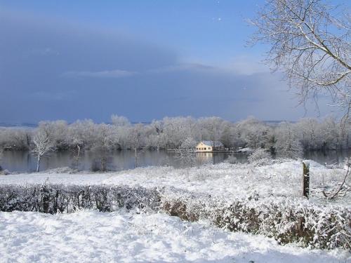 a field covered in snow with a house in the background at Chambres d'hôtes B&B Cote d'Opale La Fermette du Lac in Ardres
