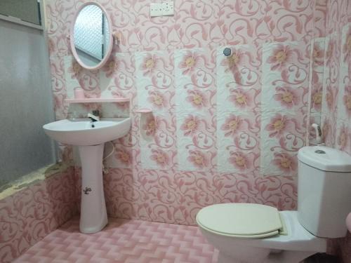 a pink bathroom with a sink and a toilet at SSA Guest House in Jaffna