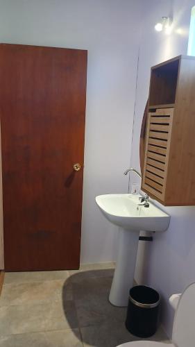 a bathroom with a sink and a wooden door at Niihau Lodge in Orufara