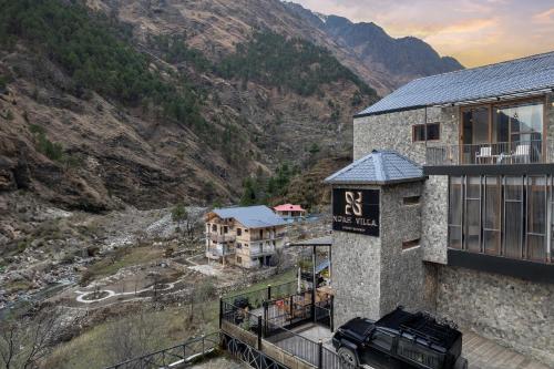a building with a sign on it next to a mountain at Echor Noah Villa Tirthan Valley in Gushaini