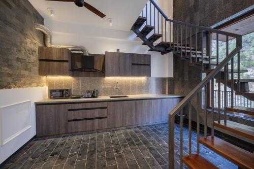 a kitchen with wooden cabinets and a spiral staircase at Echor Noah Villa Tirthan Valley in Gushaini