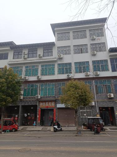 a large white building with green windows on a street at Heleju Homestay in Luoyang