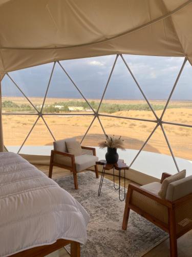 a bedroom with a bed and a view of the desert at Aman dome desert in Ḩawīyah