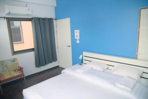 a bedroom with a bed with white sheets and a window at Before We Go Hostel Donmueang in Ban Ko