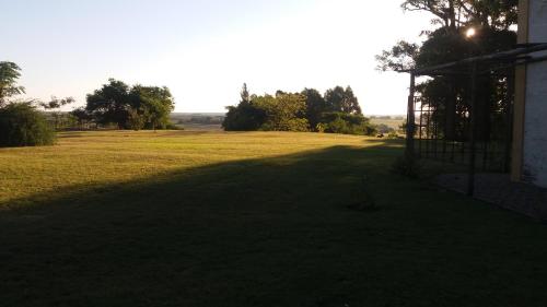 a large field of grass with a gate in the foreground at Alquimia Posada in Guichón