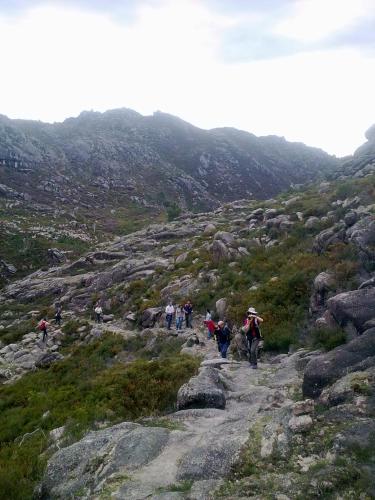 a group of people walking up a rocky mountain at Gerês Guest House in Geres