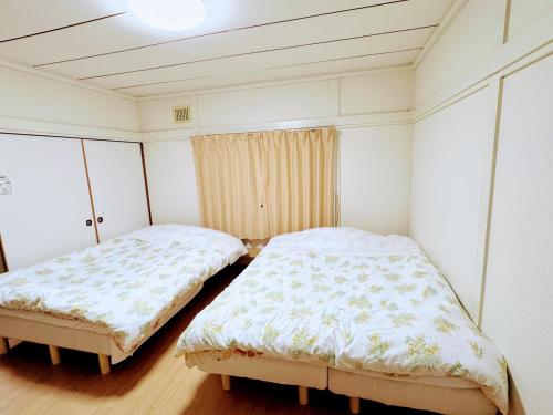 千歳市にあるHarmony chitose103ハーモニー千歳103の白い壁とウッドフロアの客室で、ベッド2台が備わります。
