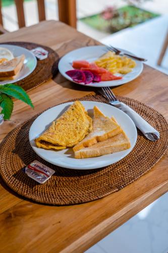 deux assiettes de nourriture sur une table avec du pain grillé dans l'établissement Nusa Dewata Cottage, à Nusa Penida