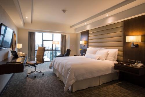 a hotel room with a large bed and a desk at Swissotel Lima in Lima