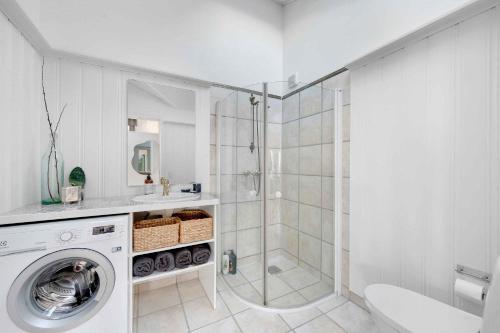 a white bathroom with a shower and a washing machine at Sea View And Charging Station For Electric Car in Hjørring