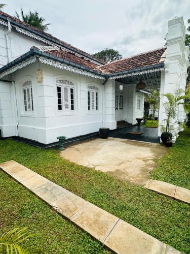 a white house with a yard in front of it at Villa 1908 in Dodanduwa
