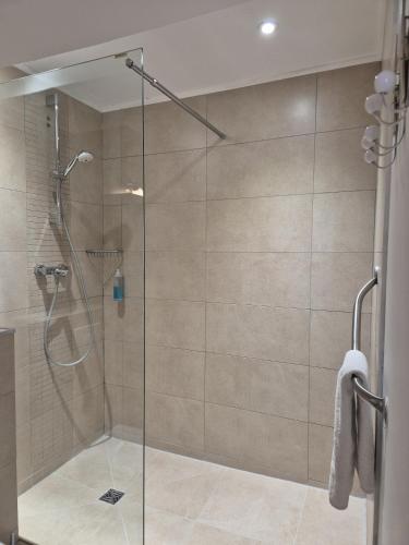 a shower with a glass door in a bathroom at Hôtel Des Argousiers in Ambleteuse