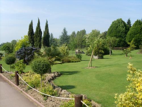 a garden with a green lawn with trees and a fence at Hotel Abbaye du Golf de Lésigny in Lésigny