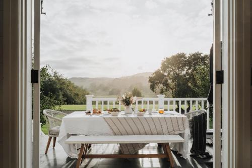 a table with a white table cloth on a porch at Linnaeus Farm, Berry - by Linnaeus Collection in Berry