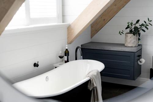 a bathroom with a white bath tub and a window at Linnaeus Farm, Berry - by Linnaeus Collection in Berry