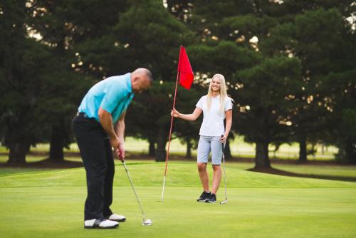 a man and a woman playing golf on a golf course at Mercure Orange in Orange