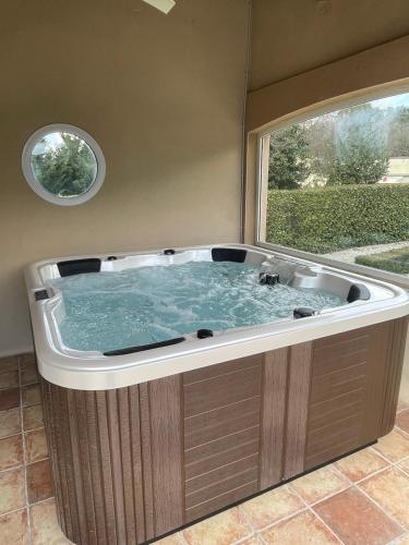 une grande baignoire dans une pièce avec une fenêtre dans l'établissement L'Olivier d'Alana - entre Cévennes et Méditerranée, à Massannes