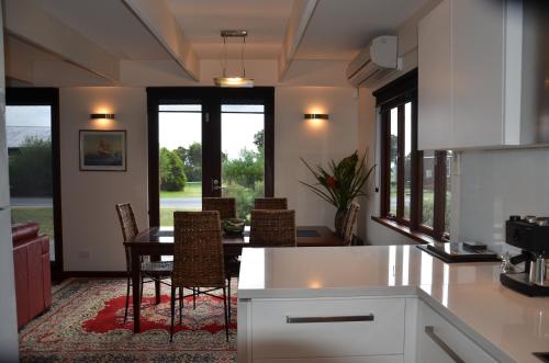 a kitchen with a table and chairs and windows at Yolla Beach House in Adventure Bay