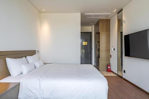a bedroom with a large white bed and a flat screen tv at Hotel Jeonju Hanok Village in Jeonju