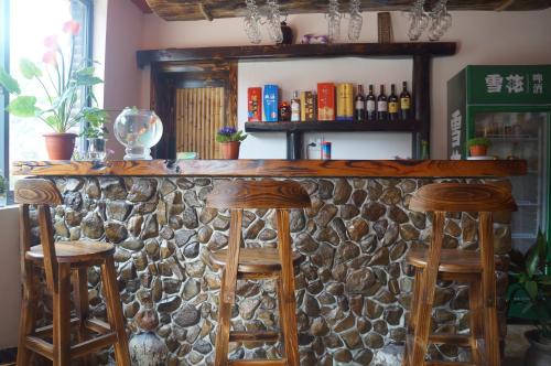 a bar with two stools and a stone wall at Mogan Guyue Guesthouse in Deqing