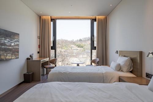 a hotel room with two beds and a large window at Hotel Jeonju Hanok Village in Jeonju