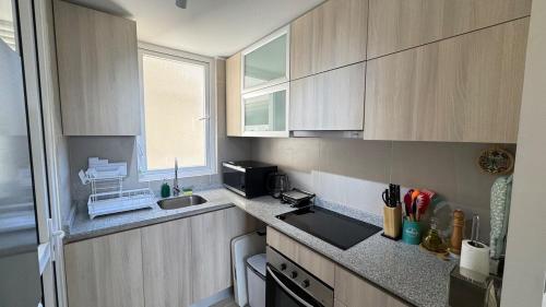 El mejor lugar - Laguna paradisíaca في لاس كروسيس: مطبخ صغير مع دواليب خشبية ومغسلة