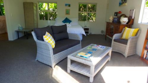 a living room with a couch and two chairs and a bed at Cathedral Cove Apartment in Hahei
