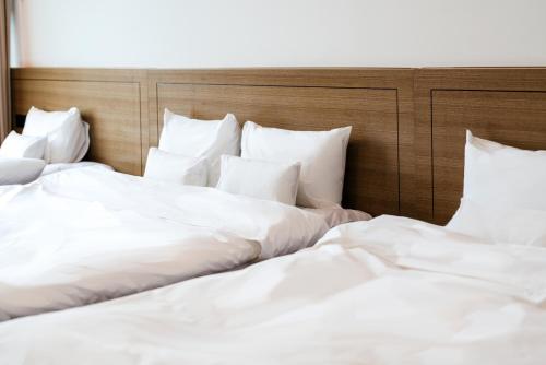 two beds in a hotel room with white sheets at Hotel Jeonju Hanok Village in Jeonju