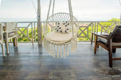 a swinging chair on a porch with a view of the ocean at Villa Lanie Lembongan in Nusa Lembongan