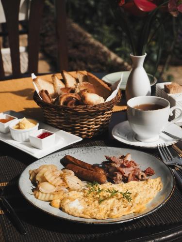a table with a plate of food and a basket of bread at Madulkelle Tea and Eco Lodge in Kandy