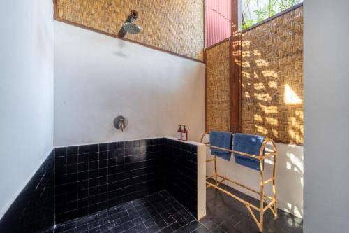 a bathroom with a black tile tub and a window at Villa Bagheera in Gili Trawangan