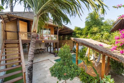 a house with a palm tree in front of it at Villa Bagheera in Gili Trawangan