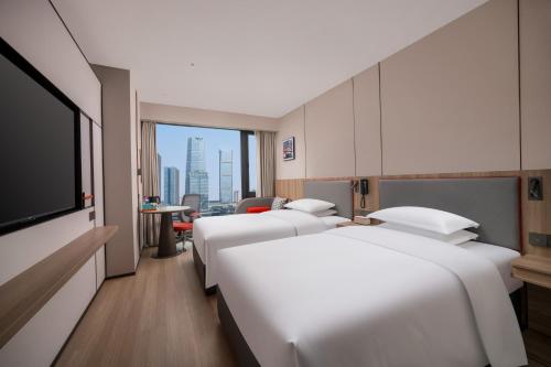 重慶市にあるHoliday Inn Express Chongqing Central Park by IHGのベッド3台と薄型テレビ付きのホテルの部屋