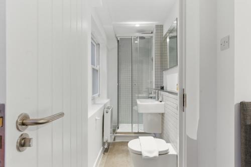 a white bathroom with a toilet and a sink at Stylish 2BR Clerkenwell Apartment Private Outdoor Space in London