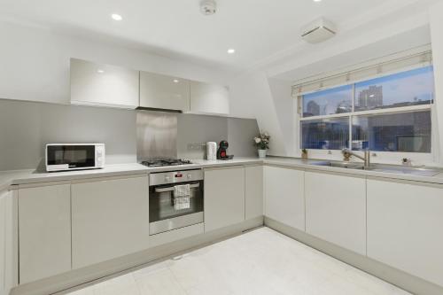 a white kitchen with white cabinets and a microwave at Stylish 2BR Clerkenwell Apartment Private Outdoor Space in London