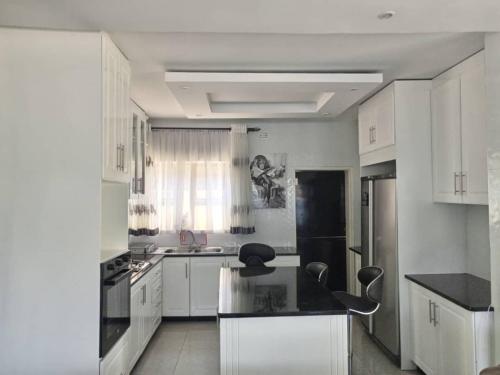 uma cozinha com armários brancos e uma bancada preta em Tourice Lodge em Victoria Falls