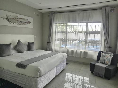 um quarto com uma cama, uma janela e uma cadeira em Tourice Lodge em Victoria Falls