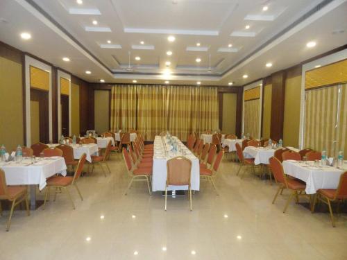 a banquet hall with white tables and chairs at Alps Residency - A Bergamont Hotel, Krishnagiri in Krishnagiri