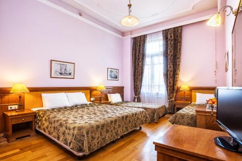 a hotel room with two beds and a television at Minerva Premier Hotel in Thessaloniki