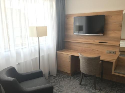 a room with a tv and a chair and a desk at Rührberger Hof Hotel & Restaurant Grenzach-Wyhlen bei Basel in Grenzach-Wyhlen