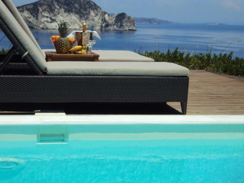 a bed sitting next to a pool with a view of the ocean at Exensian Villas & Suites in Marathias