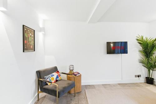 a chair in a room with a tv on a wall at Modern Clerkenwell Loft Spacious Private Terrace in London