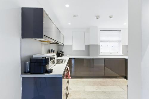 a kitchen with white cabinets and a blue counter top at Modern Clerkenwell Loft Spacious Private Terrace in London
