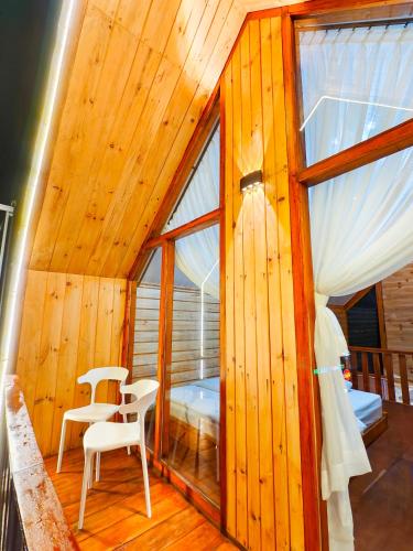a room with two chairs and a bed and windows at miarzafa cabin house in Kejajar