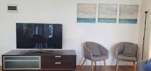 a living room with two chairs and a television at Tuggerah lakefront 4 bed 2 bath home with stunning views in Gorokan